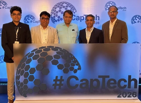 Five people standing behind a large CapTech 2026 sign.