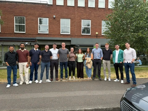 A large group standing together outside a brick building.