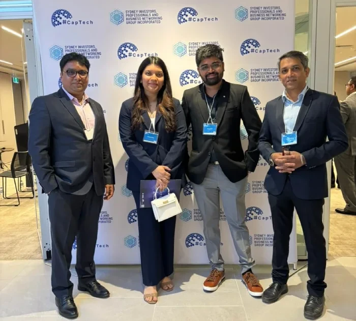 Four attendees in front of CapTech event signage in Sydney.